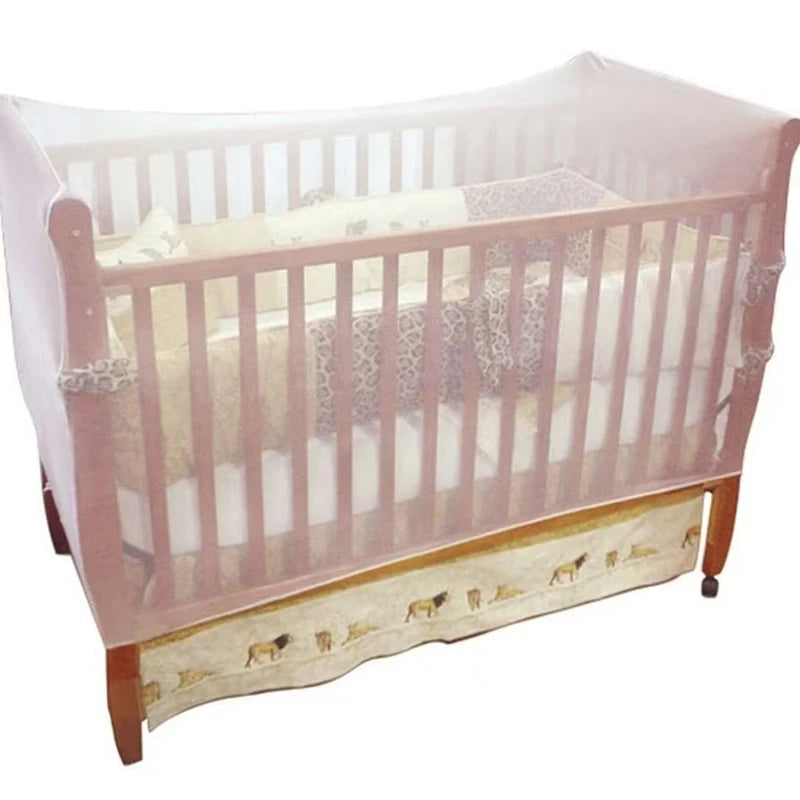 A wooden baby crib with a sheer pink mosquito net covering the sides and top.