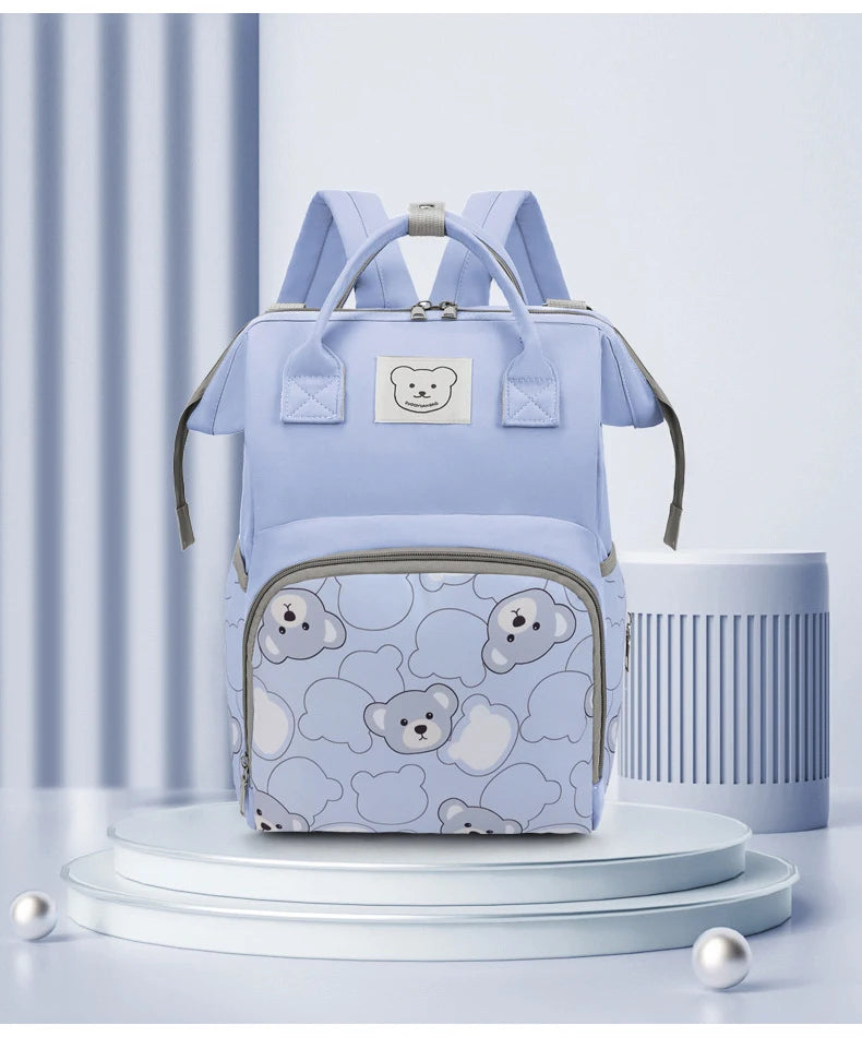 A light blue bear print waterproof diaper backpack displayed on a white stand.