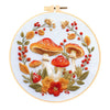 Cross stitch kit featuring an embroidered design of various mushrooms and autumn foliage.