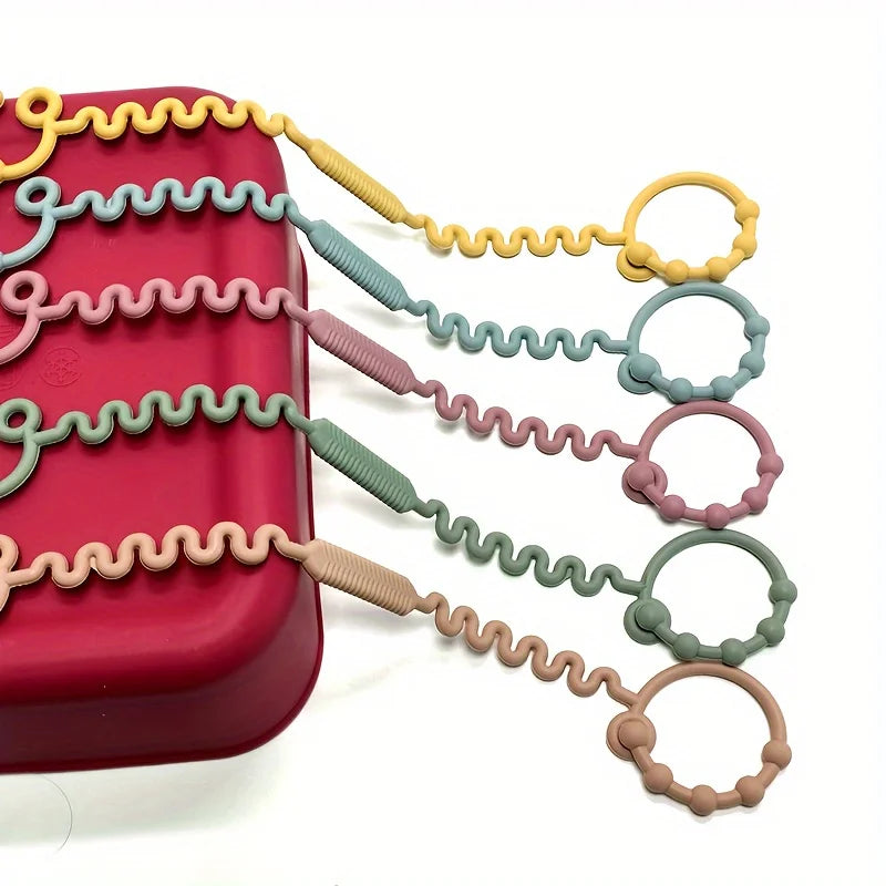 A set of silicone anti-drop pacifier clips and teethers in various pastel colors, including yellow, green, pink, and beige.