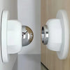 مانع باب مغناطيسي أبيض بلمسة كروم مثبت على حائط فاتح اللون.