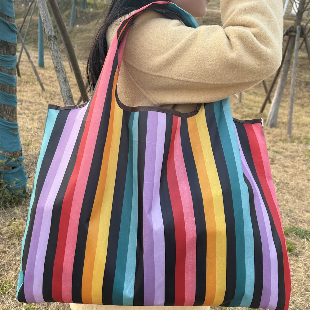A person holds a colorful striped tote bag with vertical stripes of various colors.