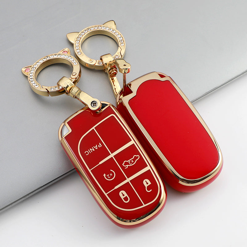 A red car key case cover with a gold keyring and decorative elements is shown on a gray surface.