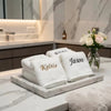 A stack of white personalized organic cotton face towels with gold lettering displayed on a marble tray.