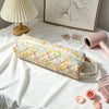 A quilted cotton hair dryer storage bag with a floral pattern rests on a white surface next to a lamp and framed art.
