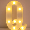 A glowing yellow LED letter night light shaped like the letter Q, illuminating the surrounding area.