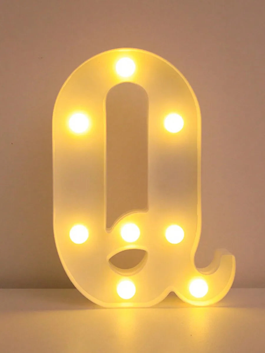 A glowing yellow LED letter night light shaped like the letter Q, illuminating the surrounding area.