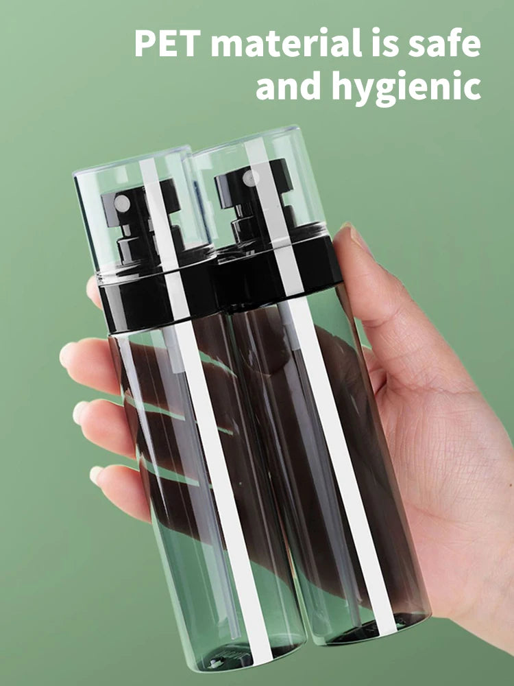 A hand holds two clear glass spray bottles filled with liquid, labeled as safe and hygienic PET material.
