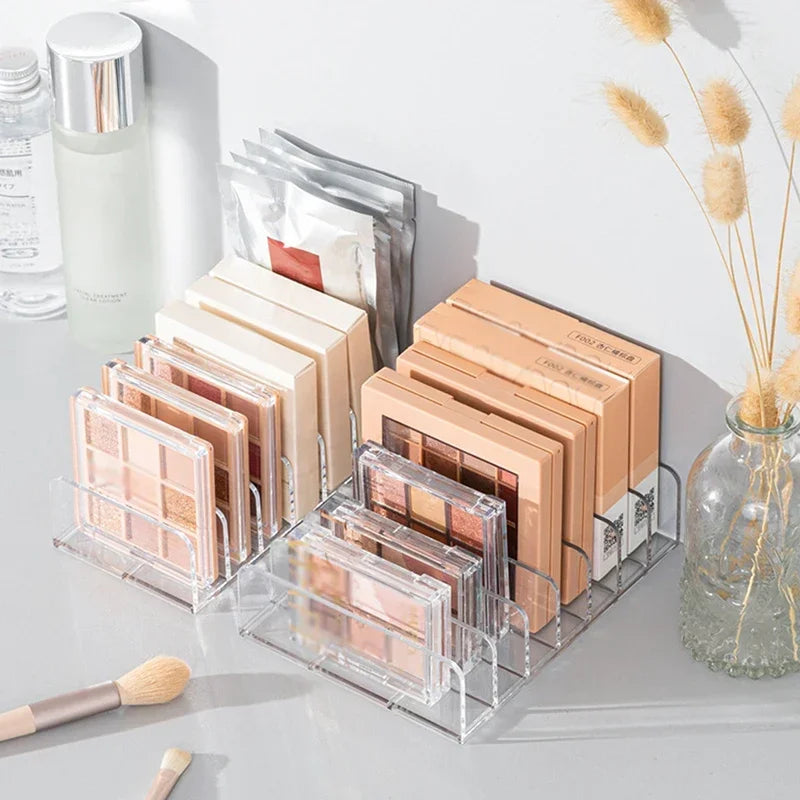 Klares Acrylorganizer mit mehreren rechteckigen Make-up-Paletten und Kosmetikartikeln.