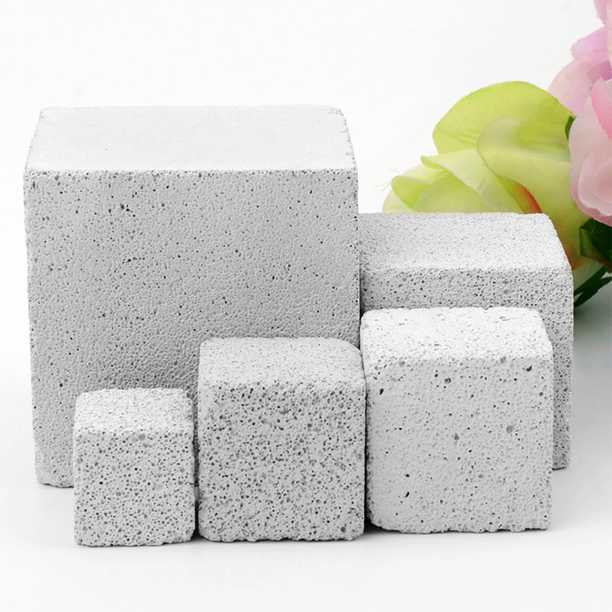A stack of white natural mineral molar stones for small pets next to a pink flower.