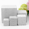 A stack of white natural mineral molar stones for small pets next to pink and green flowers.