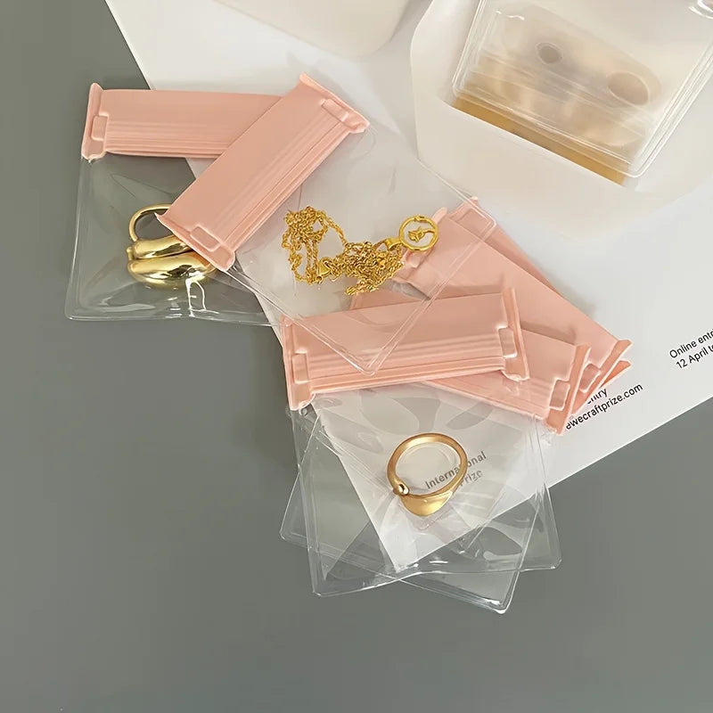 A collection of pink self-sealing storage bags containing various gold jewelry items like rings and necklaces.