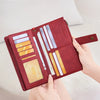A maroon leather bifold wallet with RFID protection features is shown being held open on a light background.