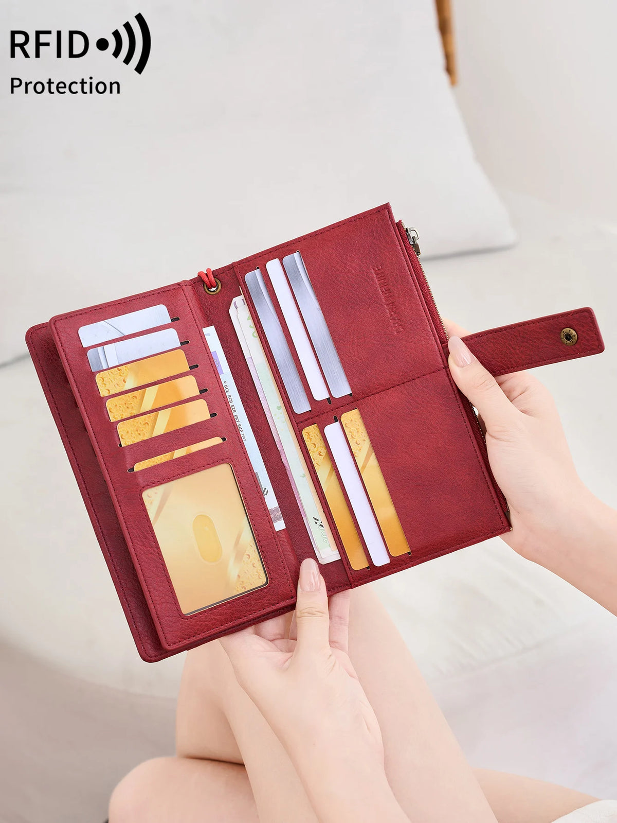 A maroon leather bifold wallet with RFID protection features is shown being held open on a light background.