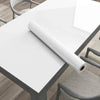 A roll of pearlescent pink marble peel and stick wallpaper lying on a white table.
