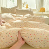 A beige duvet cover set with a cute dog print pattern and matching pillowcases is displayed on a bed.