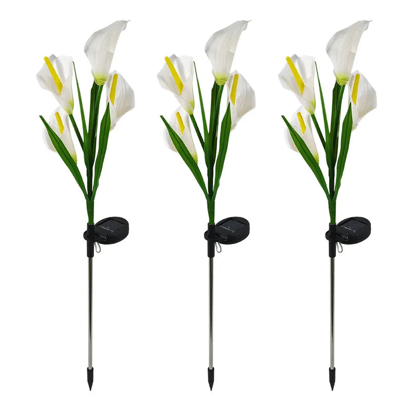 Three white calla lily LED garden lights with long metal stakes and black bases