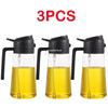 Three glass oil spray bottles with black pumps and yellow oil inside