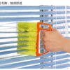 An orange dusting brush is shown cleaning the slats of a blue blind.