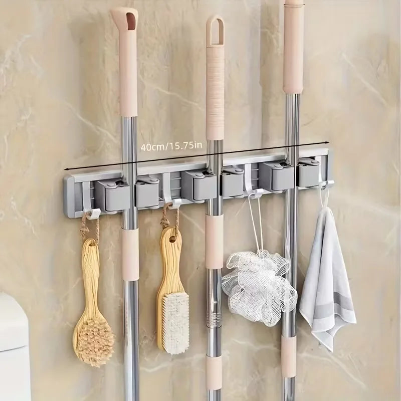 Wall-mounted metal holder for mop and broom with detachable hooks and pink grips