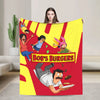A colorful cartoon illustration featuring characters in a vibrant yellow and red design on a throw blanket.