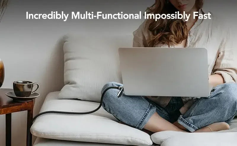 A person is using a multi-functional USB-C cable on a laptop while relaxing indoors.