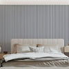 A bedroom featuring a bed with white linens against a dark gray vertical striped wall.