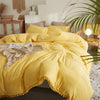A bright yellow duvet cover set with a soft, textured fabric and pom-pom trim displayed on a bed.