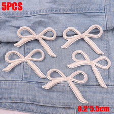 Five embroidered white cartoon bow iron-on patches displayed on a denim fabric.