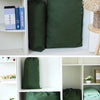 A white shelf unit displaying several dark green heavy-duty canvas laundry bags.
