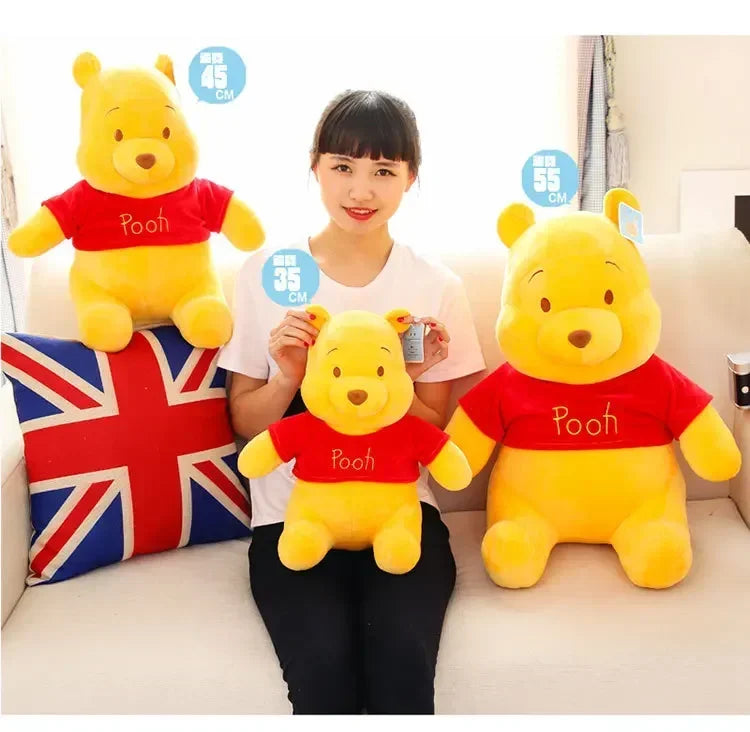 A woman is holding a yellow Winnie the Pooh plush toy, with size markers indicating 35, 45, and 55 cm.