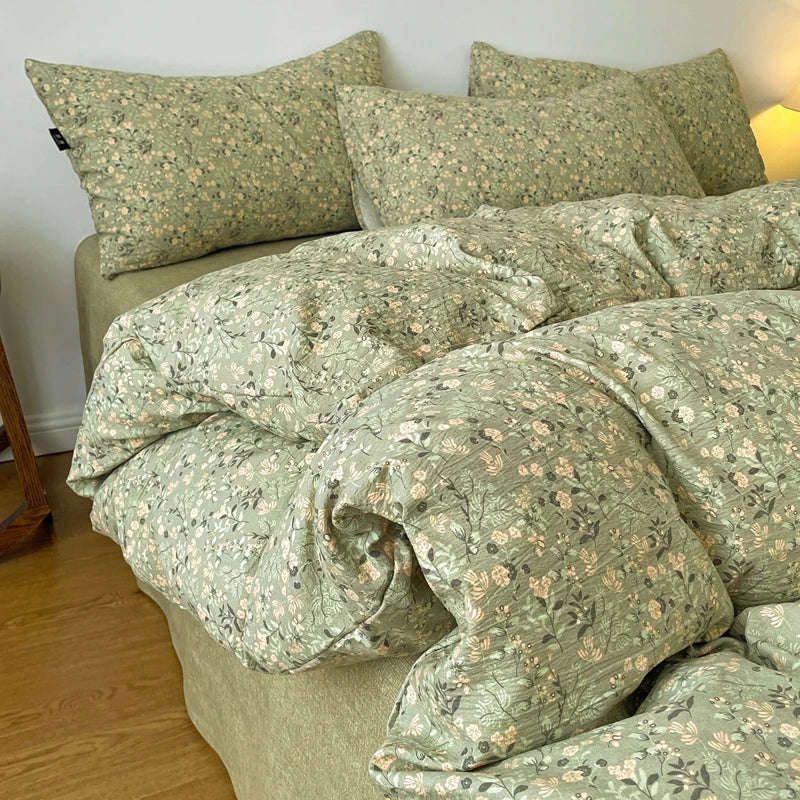 A light green floral printed duvet cover set with matching pillowcases on a bed.