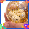 A hand holds a clear glass orb filled with gold glitter and several white squishy dumpling fidget toys.