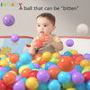 A baby is holding a red ball surrounded by many colorful soft play balls.