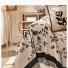 Nahaufnahme einer beige bestickten Chenille-Sofabezug mit schwarzen botanischen Mustern auf einem hellen Sofa.