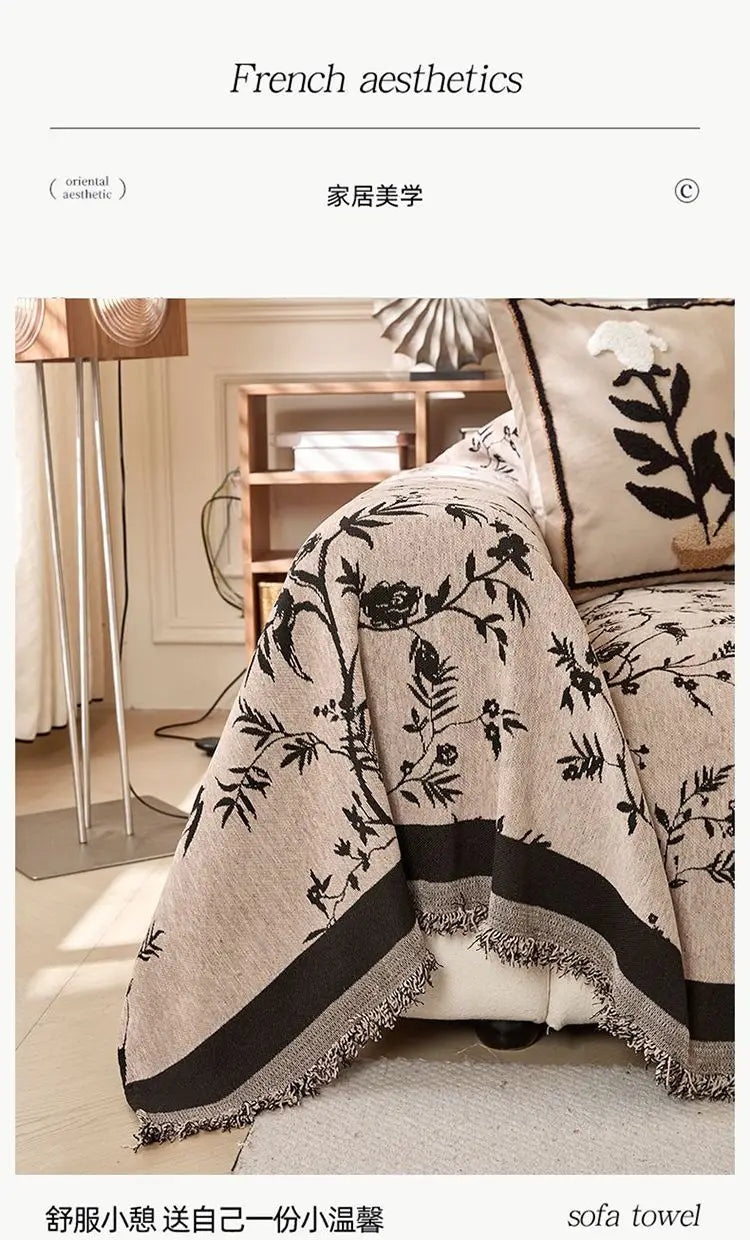 Nahaufnahme einer beige bestickten Chenille-Sofabezug mit schwarzen botanischen Mustern auf einem hellen Sofa.