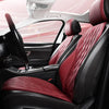 Interior view of a car seat with red quilted leather seat covers and a black steering wheel.