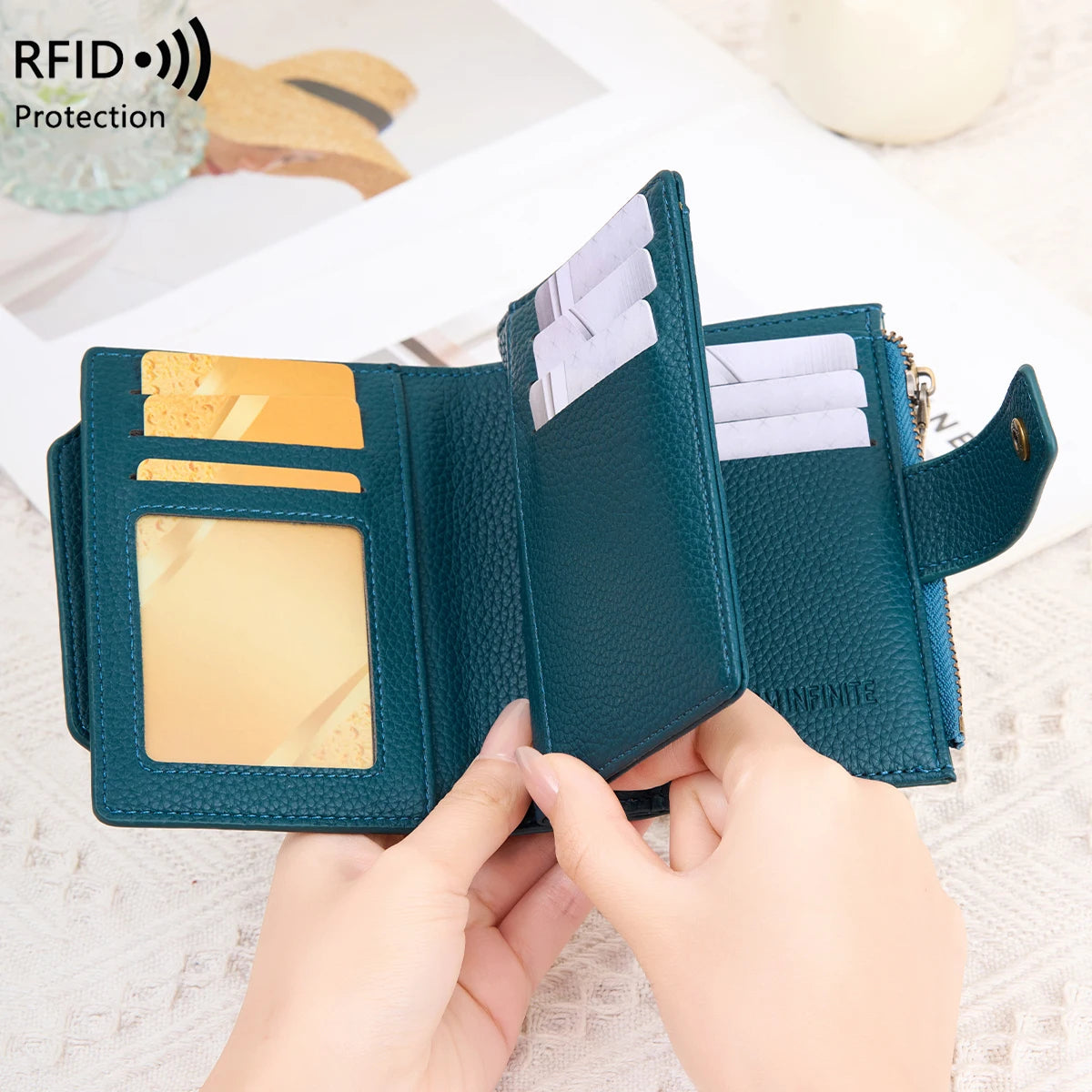 A close-up of a dark teal RFID-blocking bi-fold wallet being held open to show the interior and card slots.