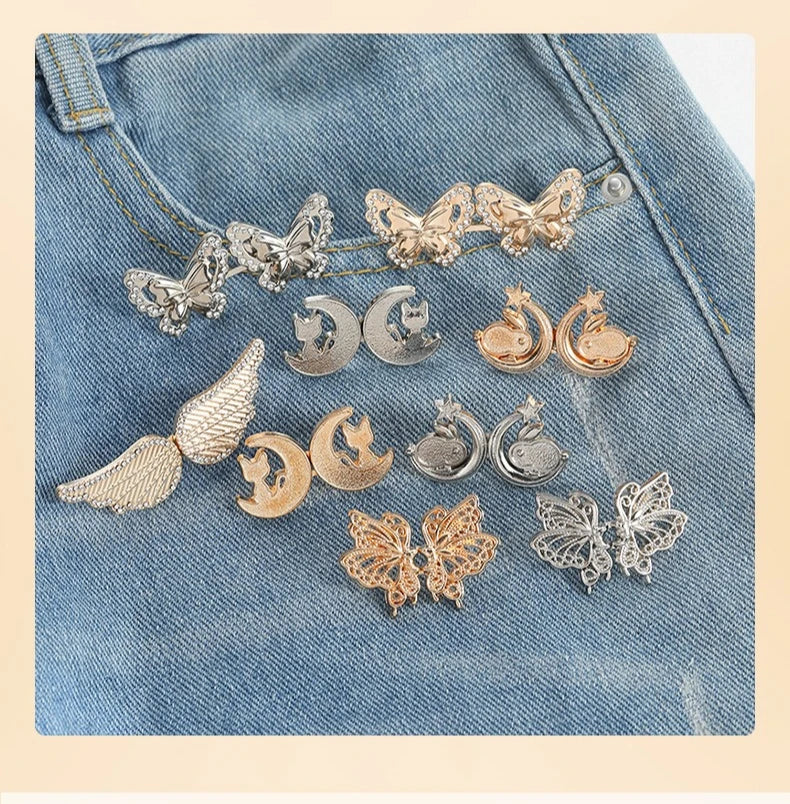 Silver and gold butterfly and crescent moon jewelry displayed on a denim fabric.