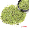 A pile of green olivine crystal stone chips in a black bowl.