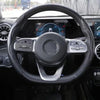 Close-up view of a black steering wheel with carbon fiber grips and an airbag cover.