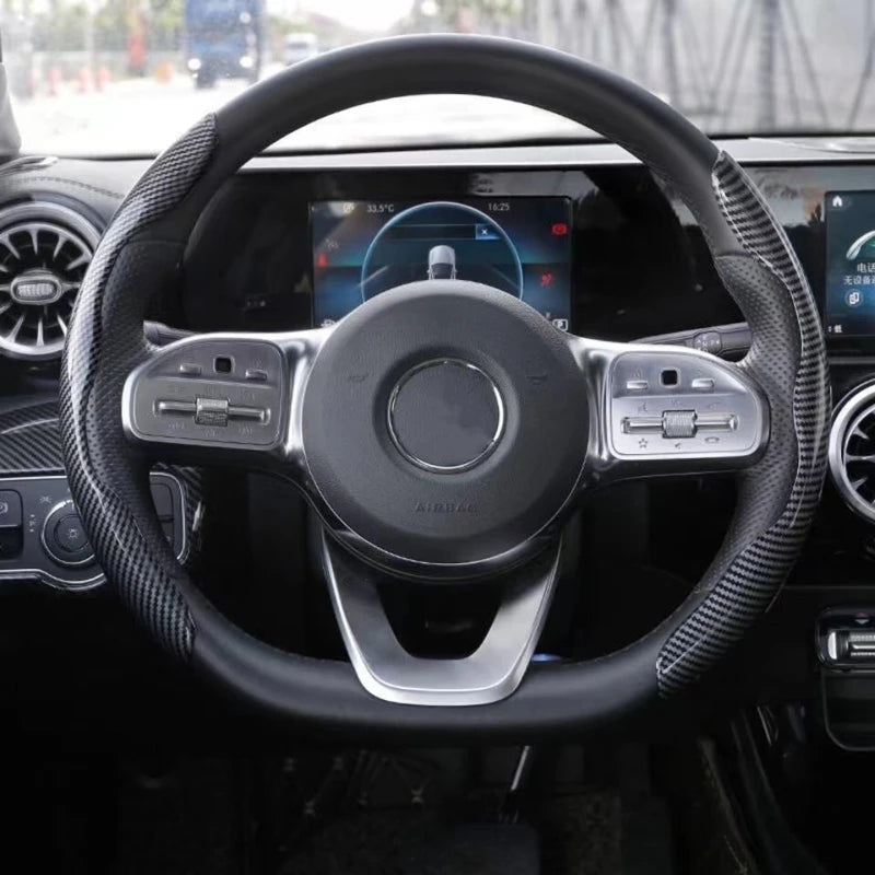 Close-up view of a black steering wheel with carbon fiber grips and an airbag cover.