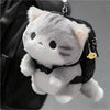 A soft grey cat plush toy is attached as a charm to a black backpack.