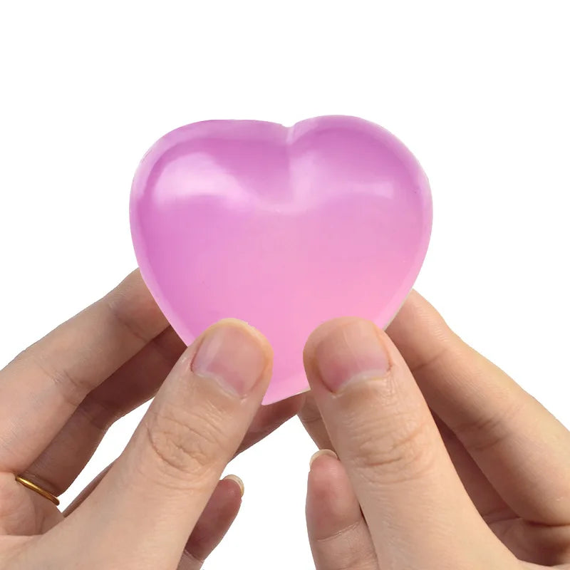 A hand is squeezing a pink heart-shaped stress relief toy.