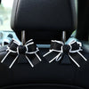 Black bow-shaped car seat back hook with storage visible on a vehicle seat.