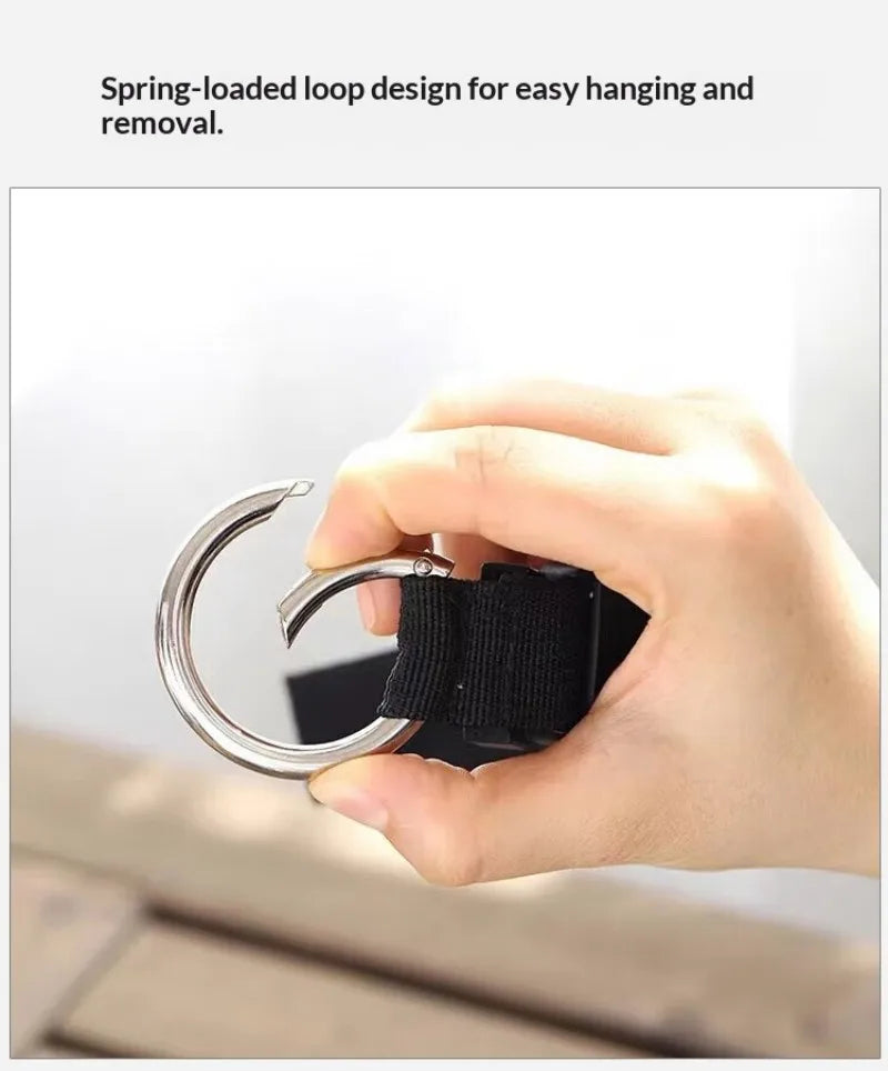 A hand is demonstrating a spring-loaded loop design for easy hanging and removal on an adjustable travel luggage strap.