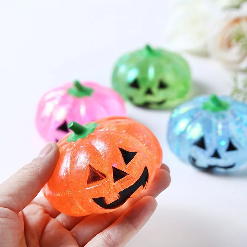 Eine Hand hält einen orangen Kürbis-Maltose-Druckball-Fidget-Spielzeug vor einem weißen Hintergrund.