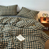 A plaid duvet cover in olive green and beige tones with a grid pattern is displayed on a bed.