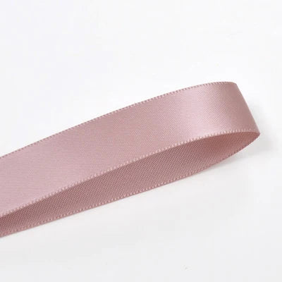 A roll of double face satin ribbon in a dusty rose color.