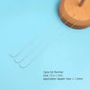 Three curved stainless steel beading needles laid diagonally on a light blue surface.